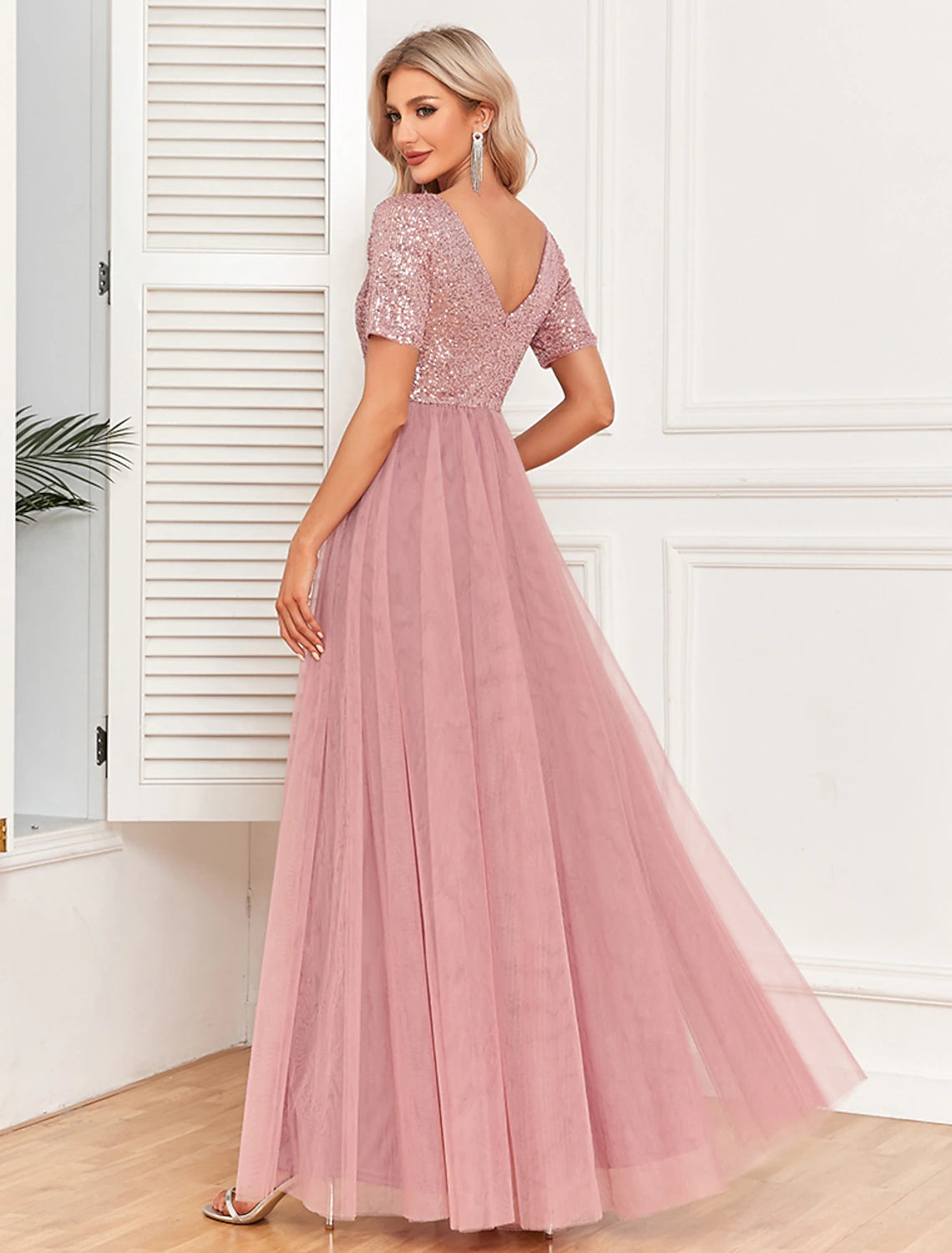 Side view of a woman in a pink sequin maxi dress.