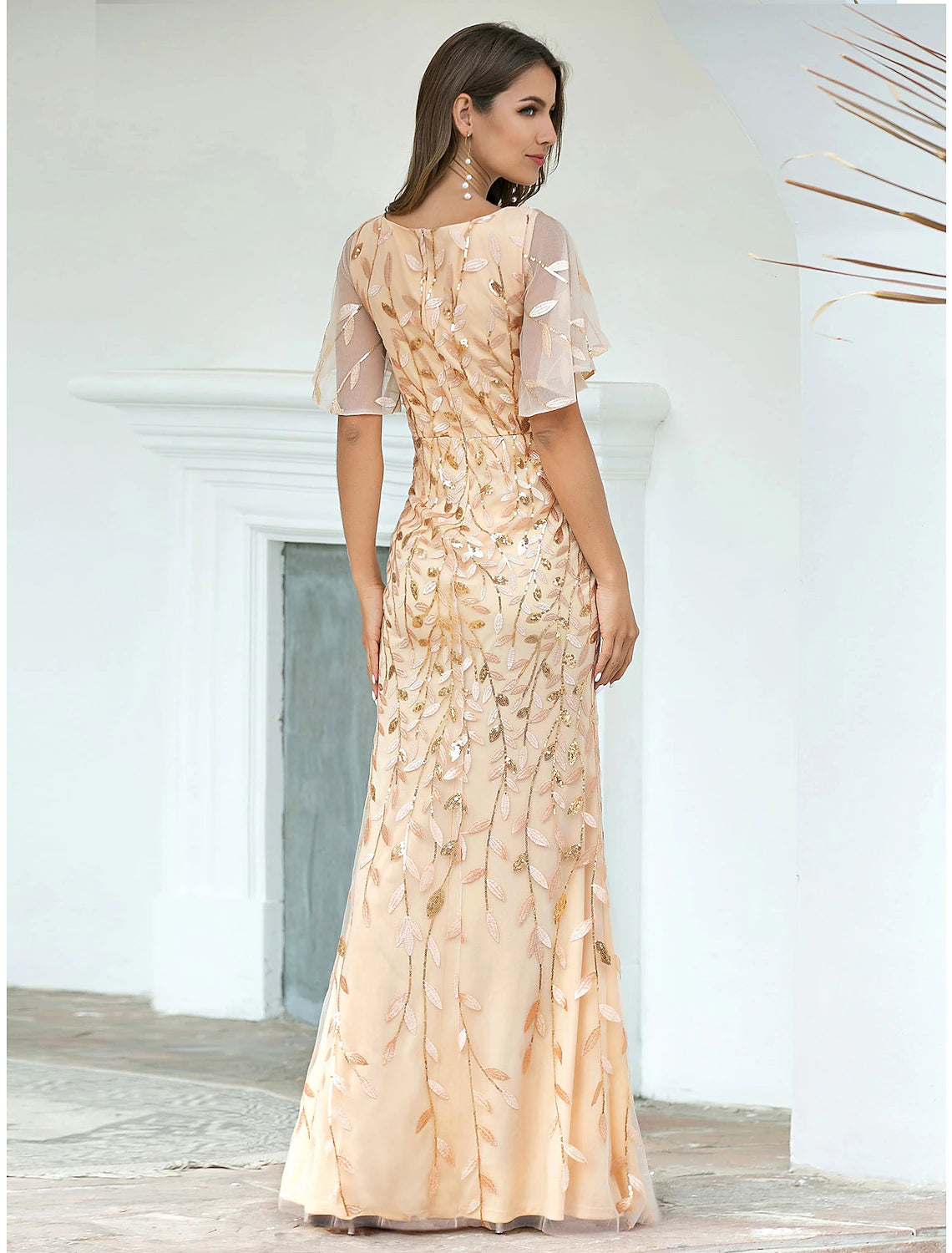 Model showcasing the side profile of a sequined V-neck short sleeve mermaid gown.