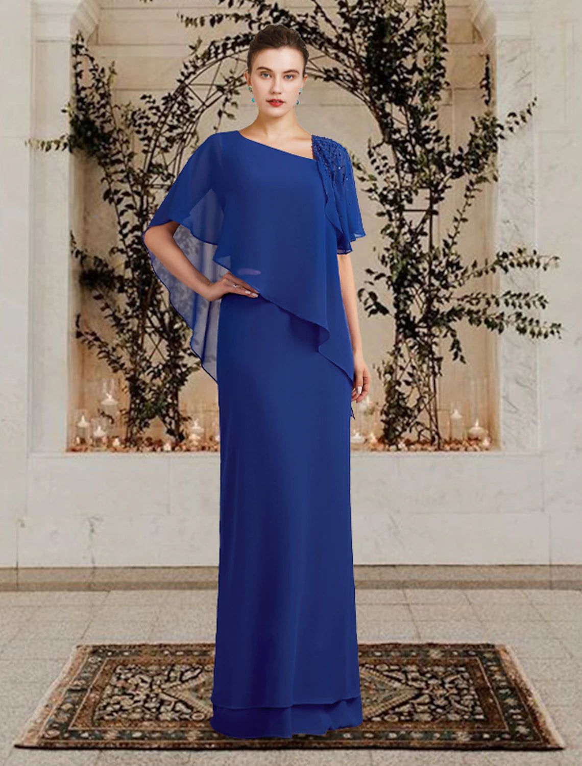 A woman wearing an elegant floor-length sheath/column Mother of the Bride dress with a bateau neck and short sleeves.