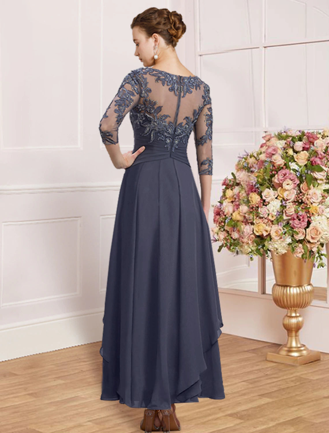 Model in a purple sheath column dress, showcasing back detail and pleats.