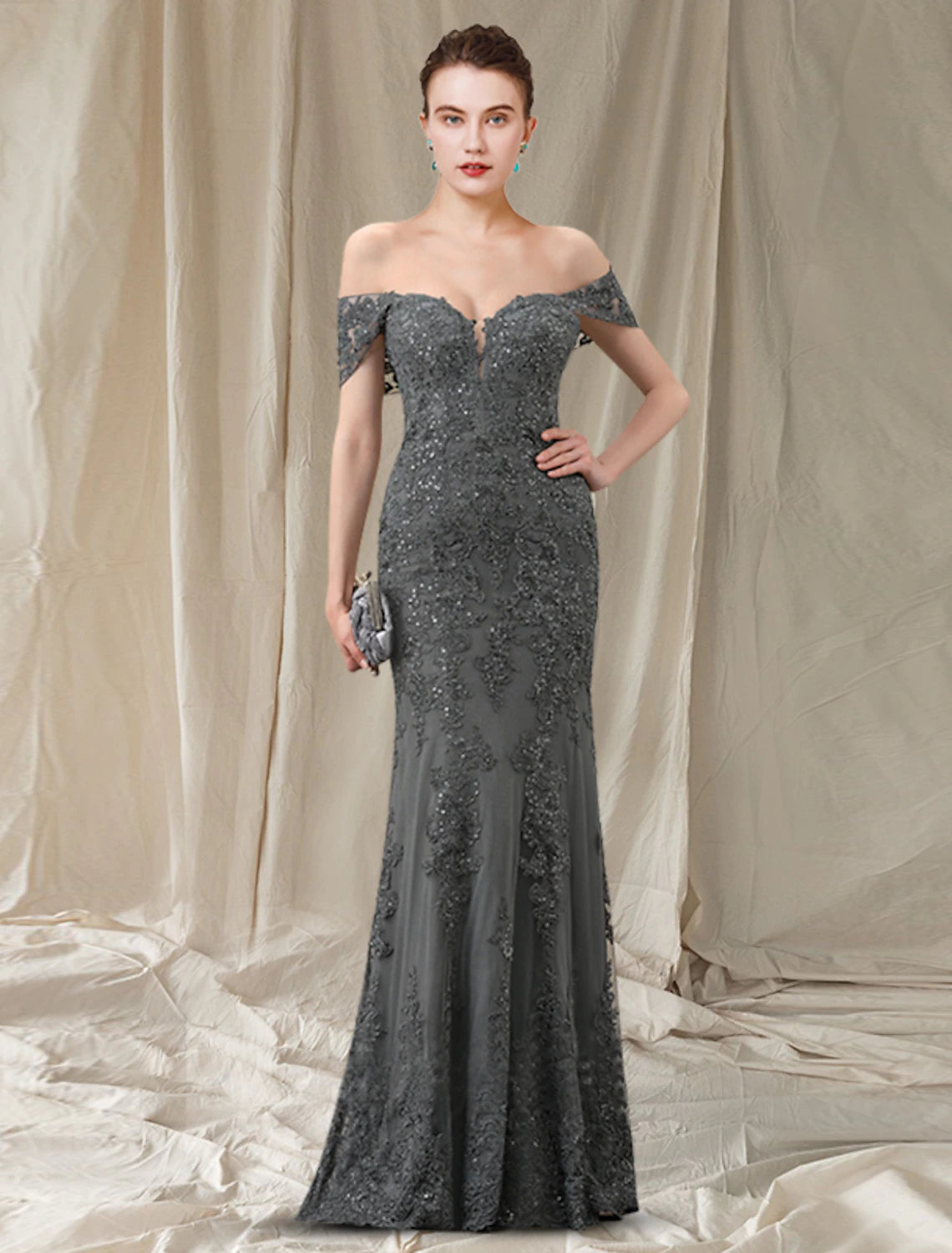 Woman wearing an elegant off-shoulder sequined lace sheath Mother of the Bride dress.