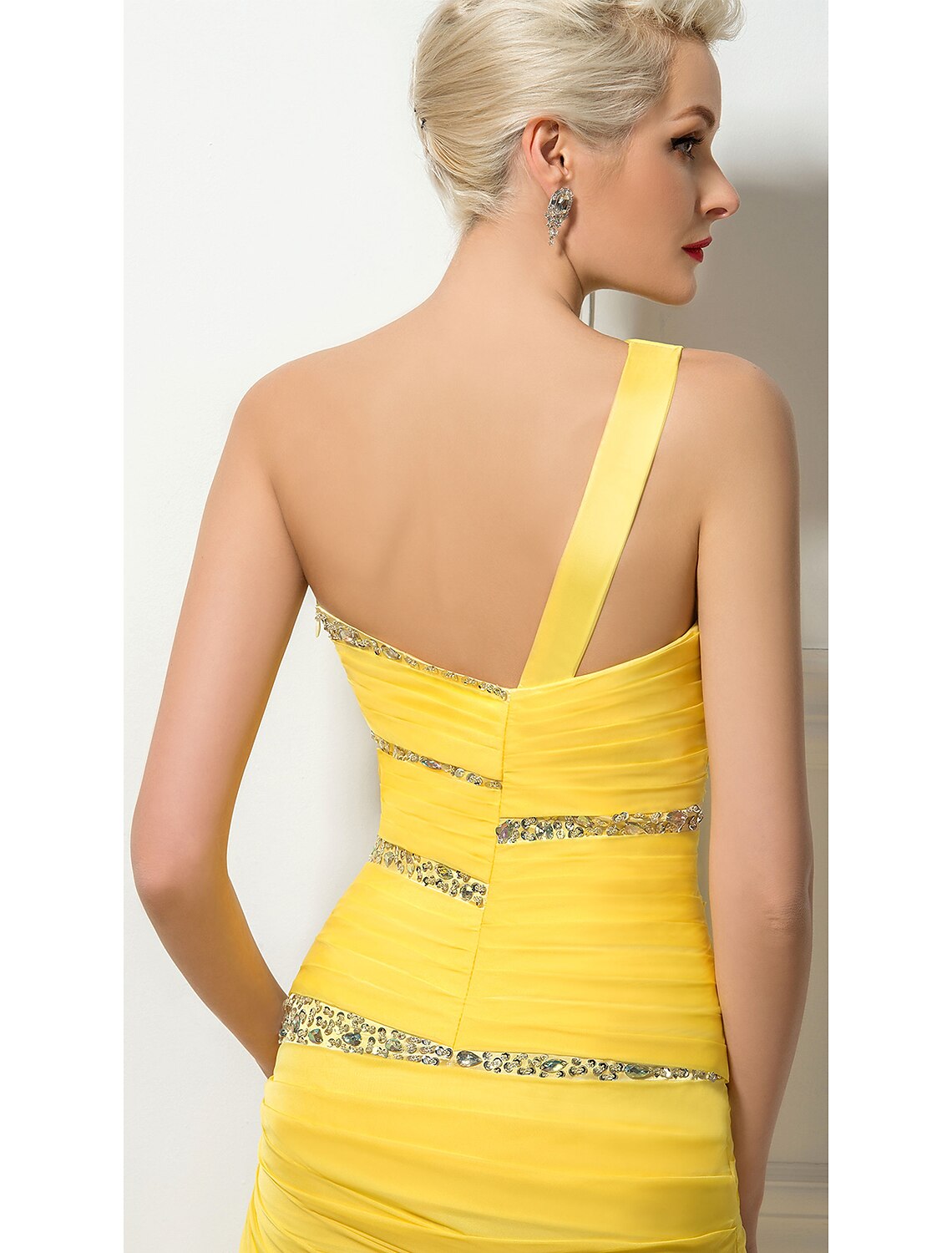 Close-up of the ruched and sequin details on a light-colored one-shoulder evening gown.