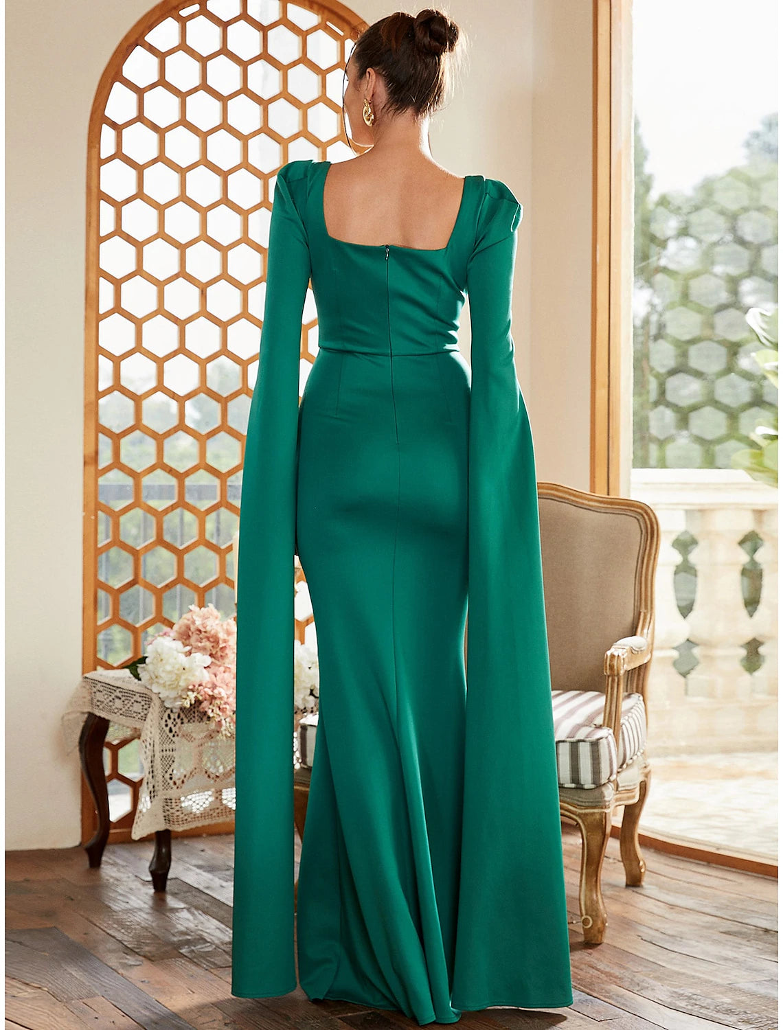 Side view of a woman in a navy pleated long-sleeve formal dress.