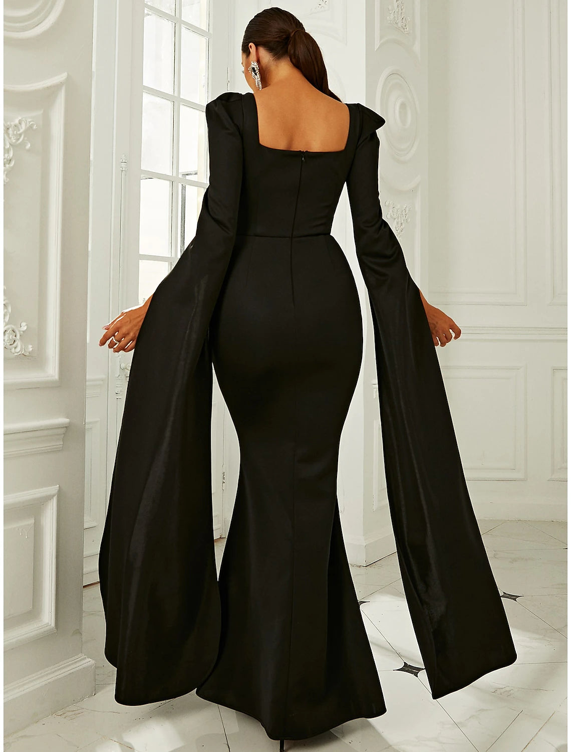 Front view of a woman posing in the elegant navy long-sleeve formal gown.