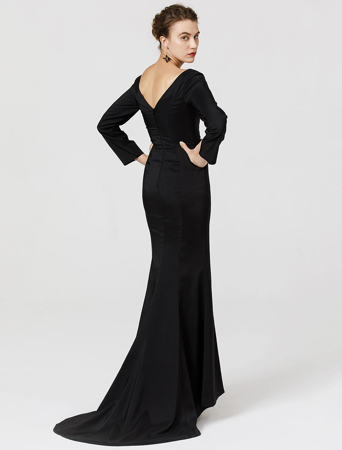 Side view of a woman in a dark stretch satin prom dress, showing long sleeves and sweep train.
