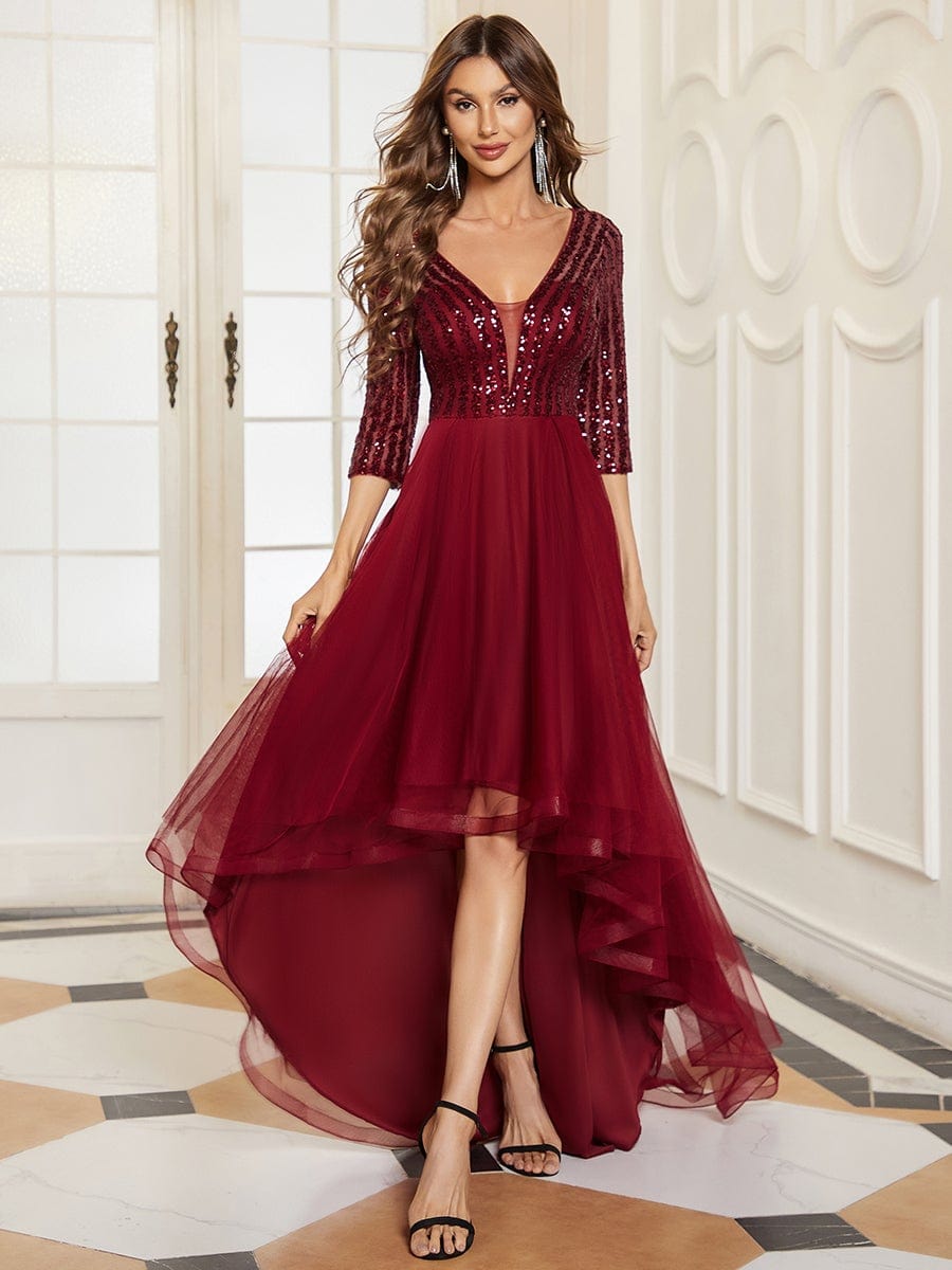Woman wearing a red sheer sequin long sleeve high-low evening dress.