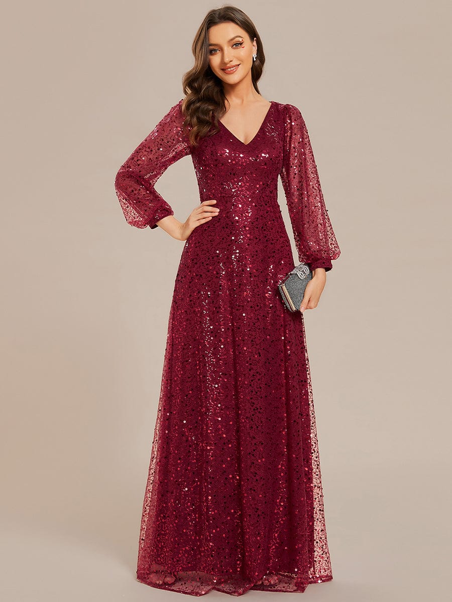 Woman wearing a red shimmering sequin A-line evening dress with V-neck and long lantern sleeves.