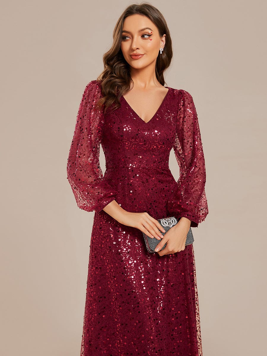 Close-up of the shimmering sequin fabric and long lantern sleeve detail on a red evening dress.