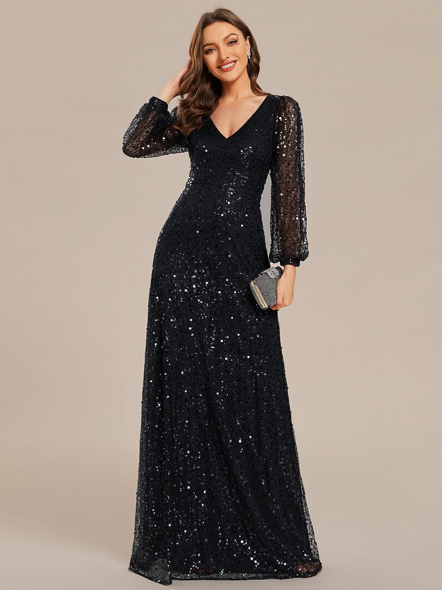 Woman wearing a black shimmering sequin A-line evening dress with V-neck and long lantern sleeves.