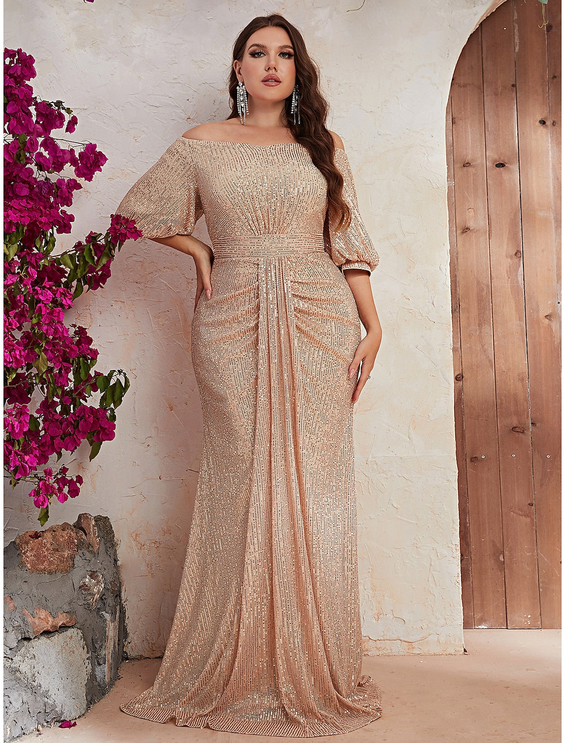 Woman wearing a sparkling A-line off-shoulder long sleeve formal gown.
