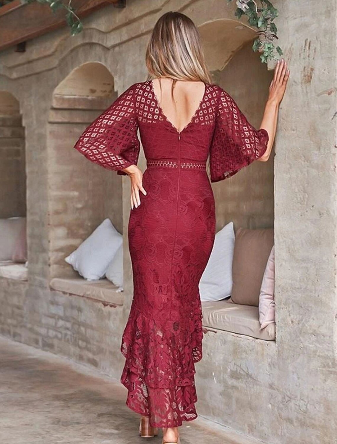 Back view of a woman in a red wine lace midi sheath dress.