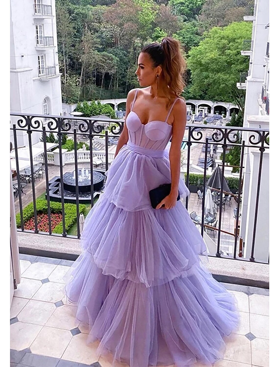 A woman wearing an elegant floor-length sweetheart tulle ball gown with ruched details.