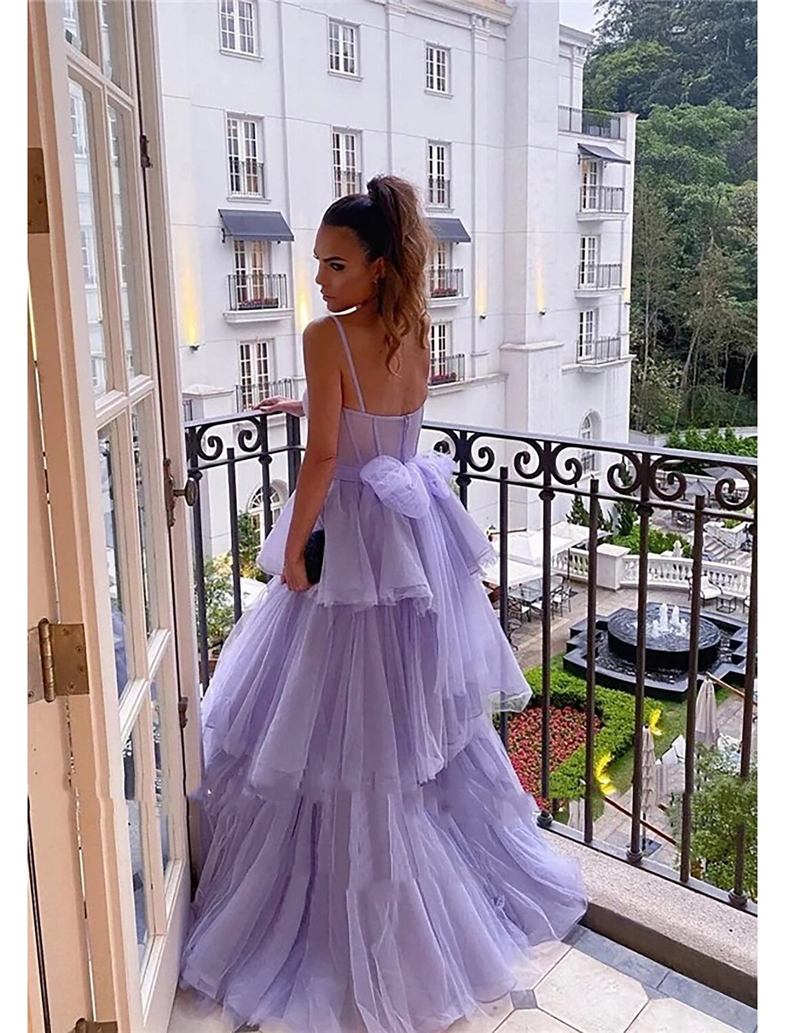 A woman posing in a backless sweetheart ball gown, showcasing the intricate pleats and flowing skirt.