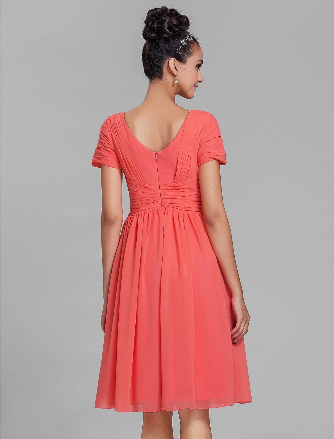Back view of a model in a teal knee-length chiffon bridesmaid dress.