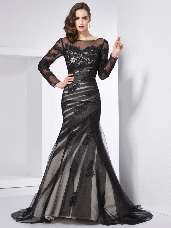Elegant woman wearing a long-sleeved trumpet mermaid dress with jewel neck and intricate appliques.