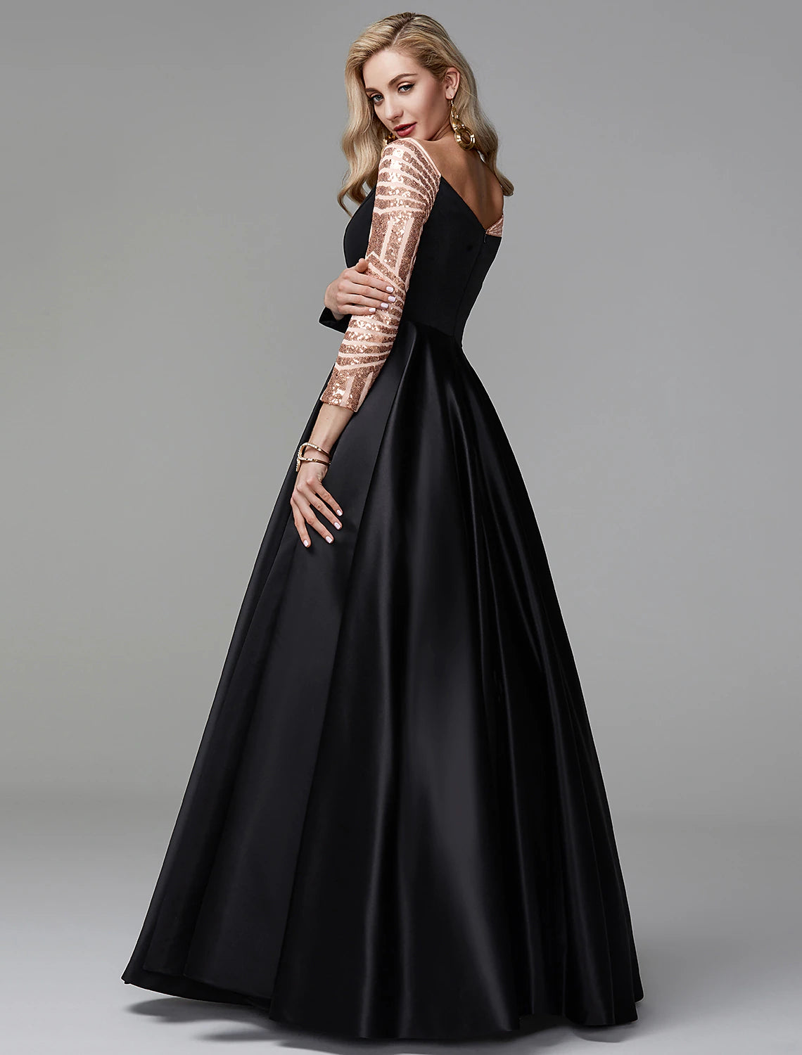 Side view of a woman in a long sleeve off-shoulder satin ball gown, showing the floor-length skirt.