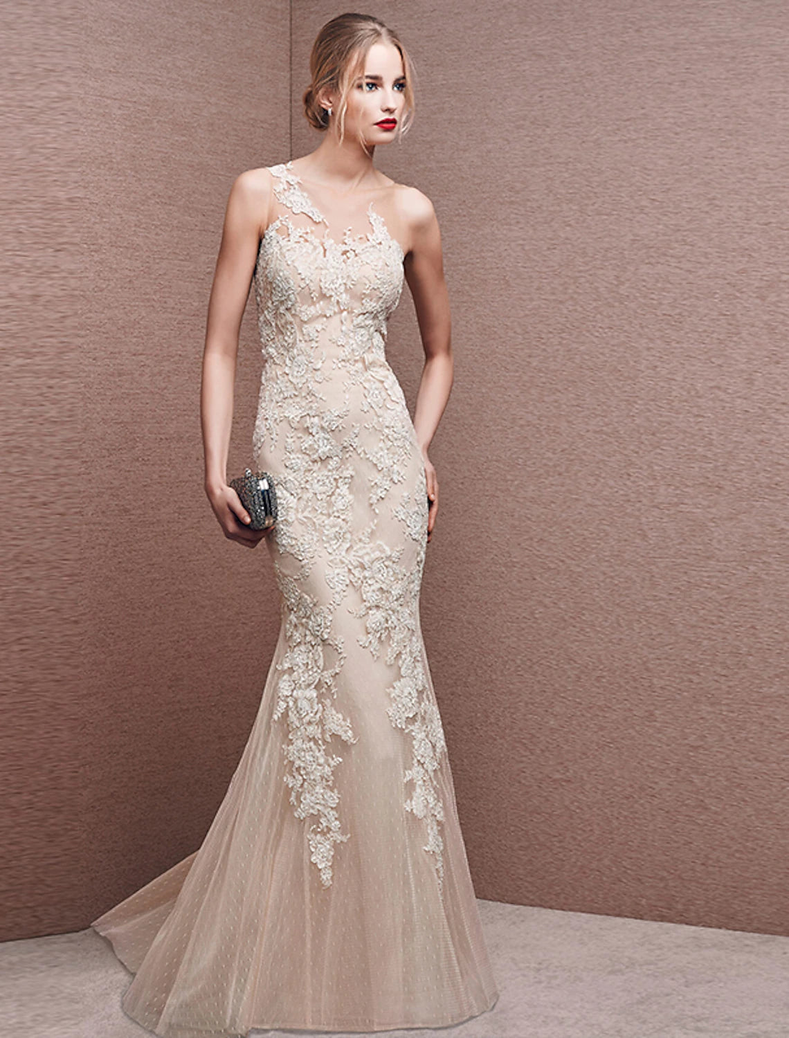 Model wearing a white mermaid trumpet formal gown with illusion neckline and lace appliques.