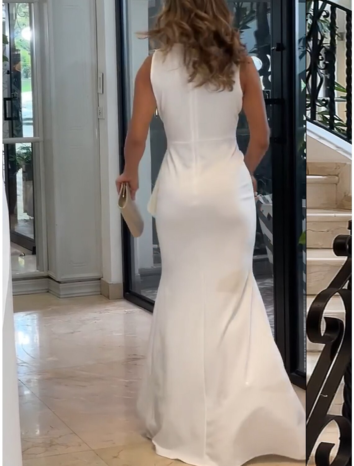 Back view of a model in a white V-neck ruffle maxi dress.