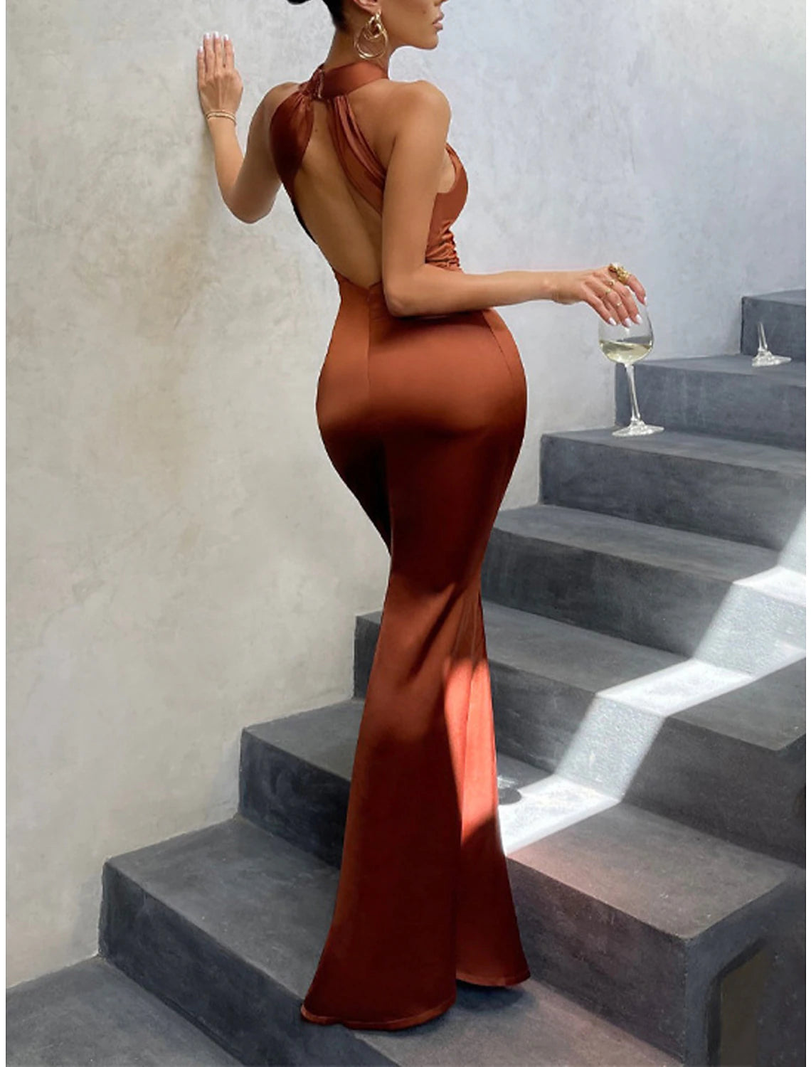 Woman in a brown halter neck backless maxi dress.