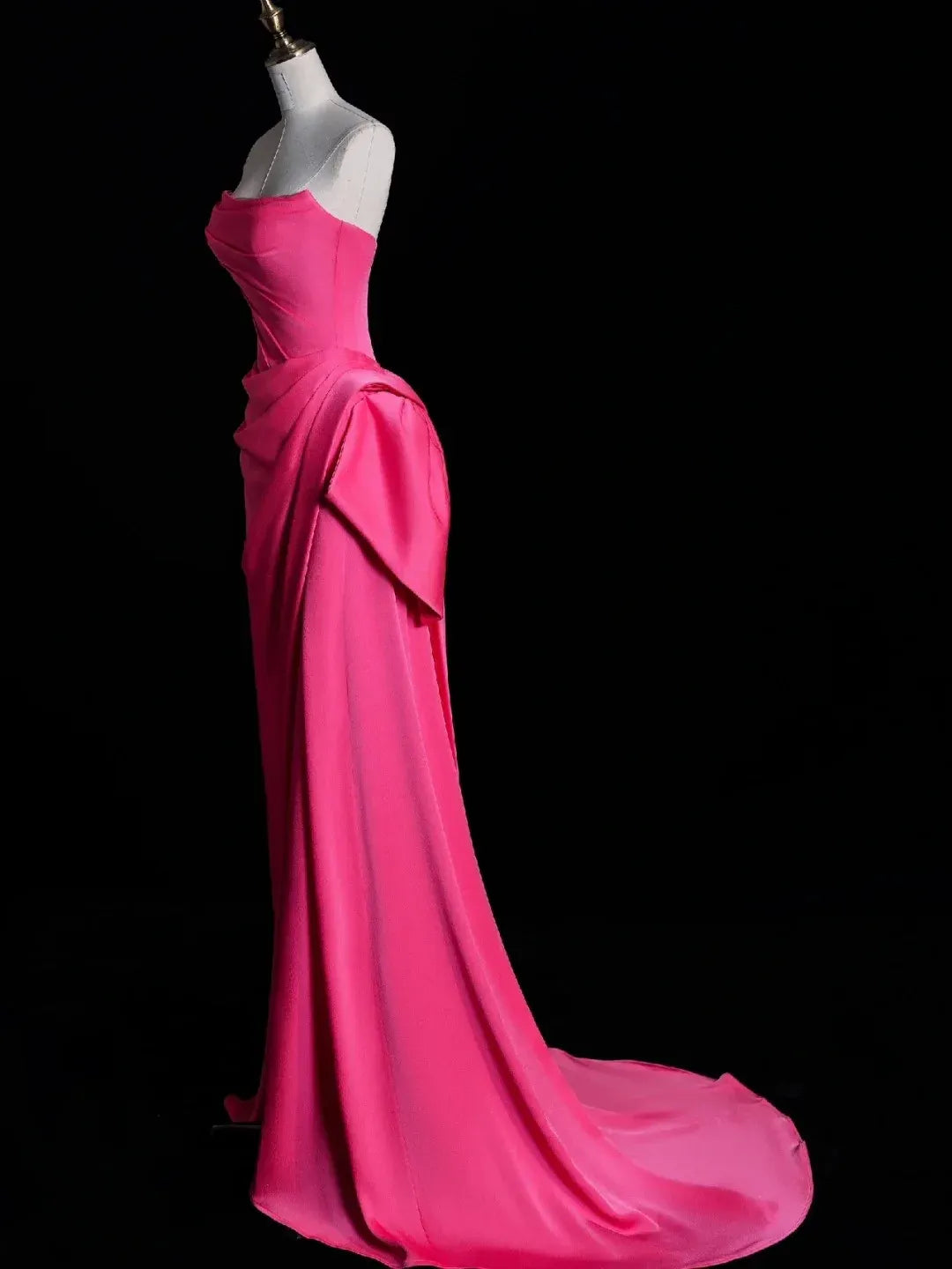 Side profile of fuchsia strapless dress showing hip bow and waist cutout.