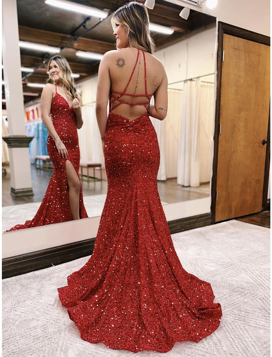 Back view of a woman in a sparkling sequined mermaid gown, highlighting the backless detail and sweep train.