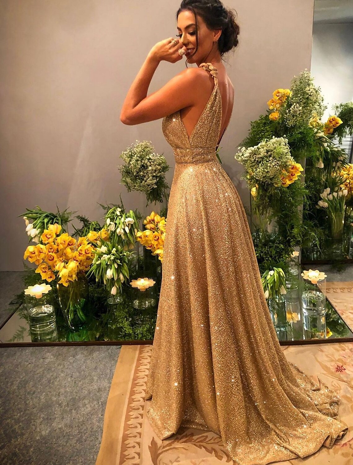 Model wearing a glittering A-line prom dress with spaghetti straps and rhinestone details.