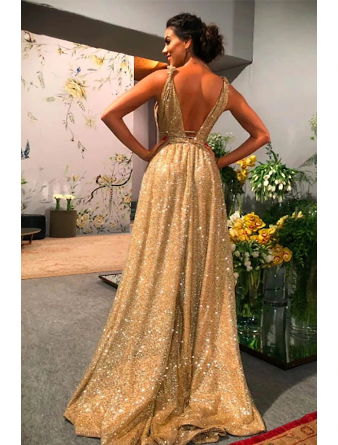 Back view of a model in a backless stretch satin evening gown with a sweep train.