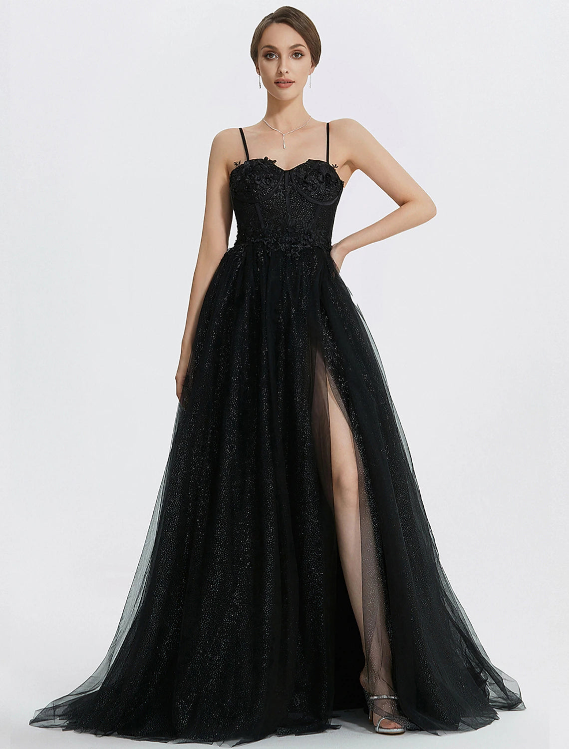 Woman wearing a glittering A-line prom dress with sweetheart neckline and floral appliques.