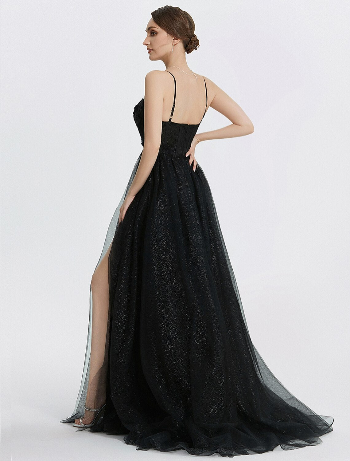 Side view of a woman in a glittering A-line tulle prom dress with delicate appliques.