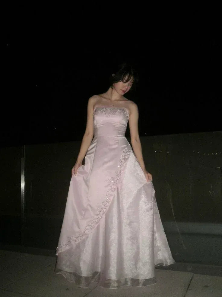 Front view of a model wearing a romantic pink strapless embroidered satin ball gown wedding dress.