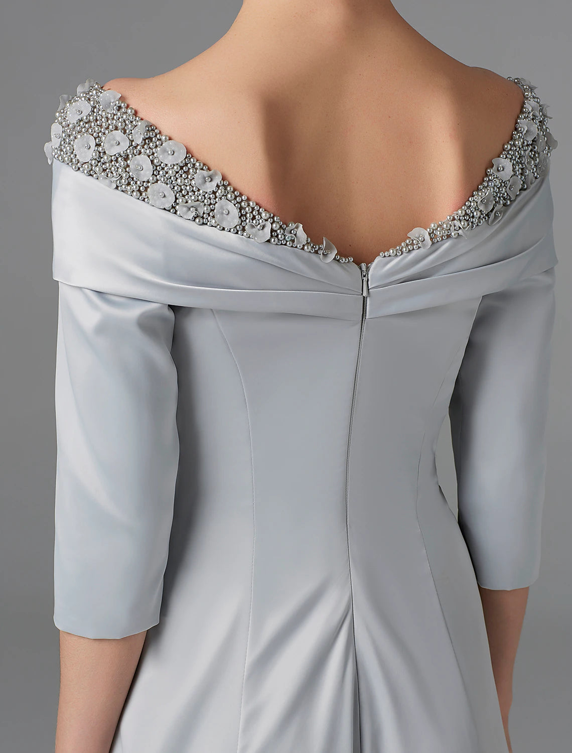 Elegant woman seated, showcasing the flow and details of the sparkling mother of the bride gown.