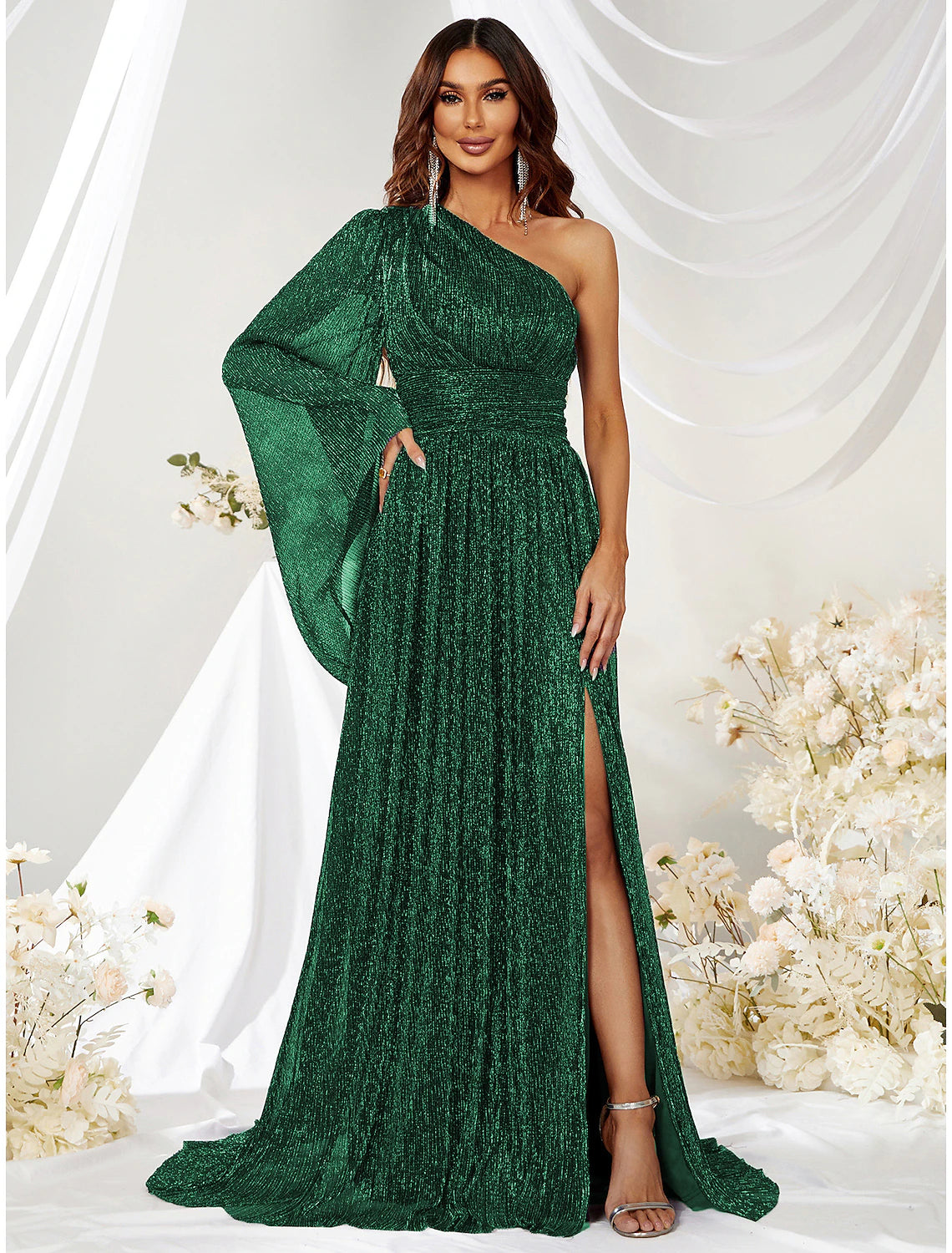 Model wearing a sparkling green one-shoulder A-line gown with a high slit and long sleeve.