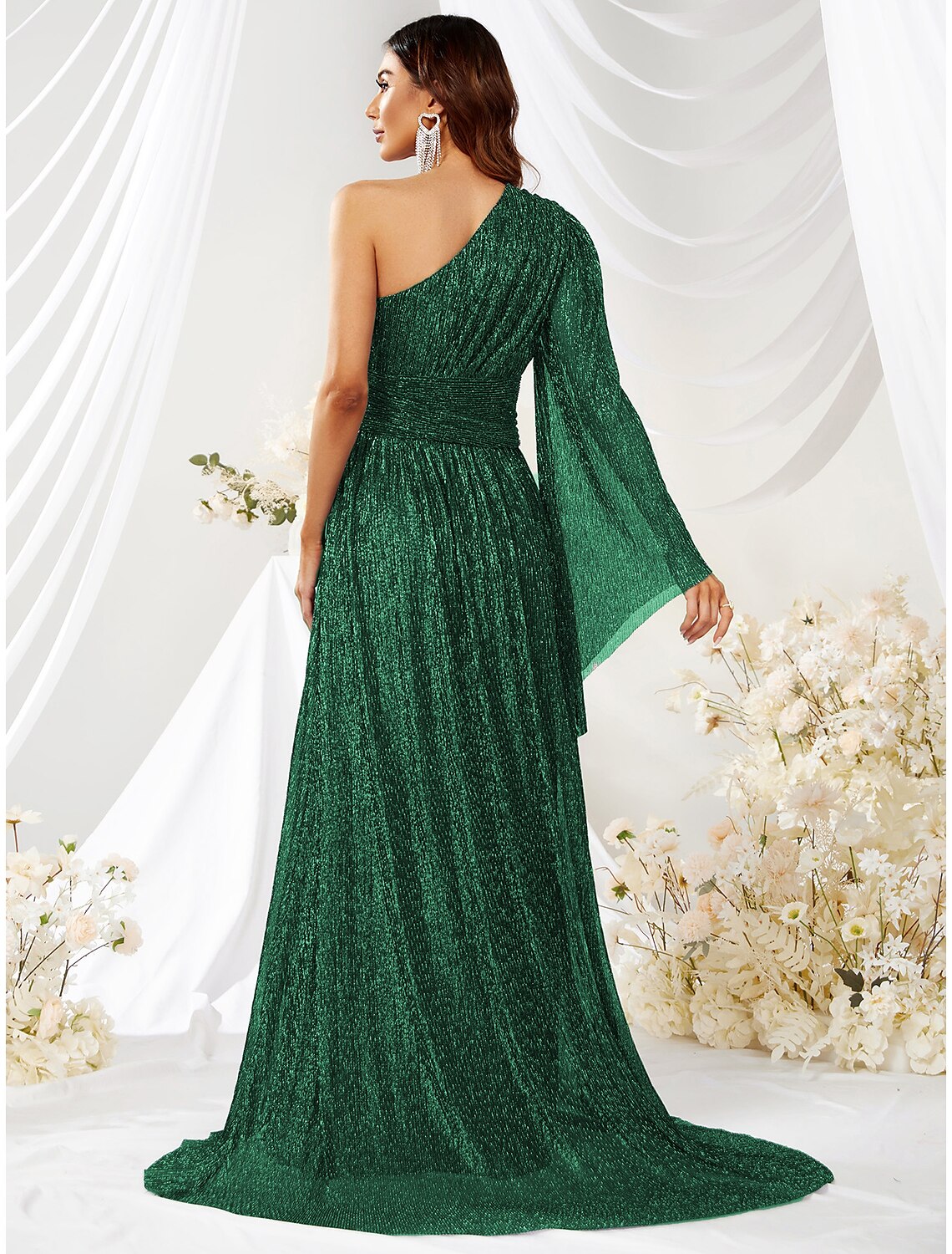 Model posing in a green glitter A-line formal dress with one long sleeve and a sweep train.