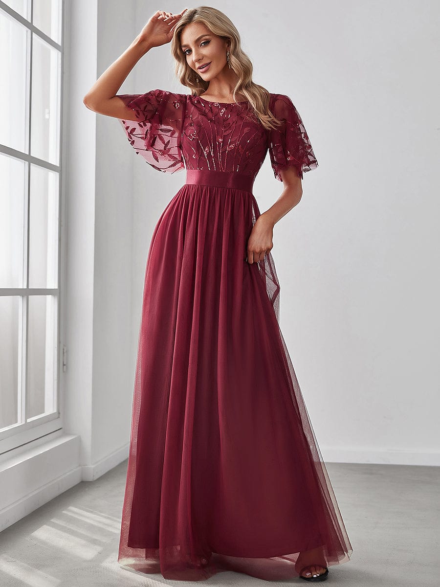 A woman in a burgundy Weitese A-line sequin leaf maxi dress with sleeves.