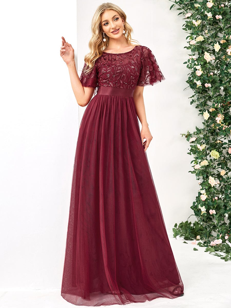 Full length view of a woman posing in a burgundy Weitese A-line sequin dress with sleeves.