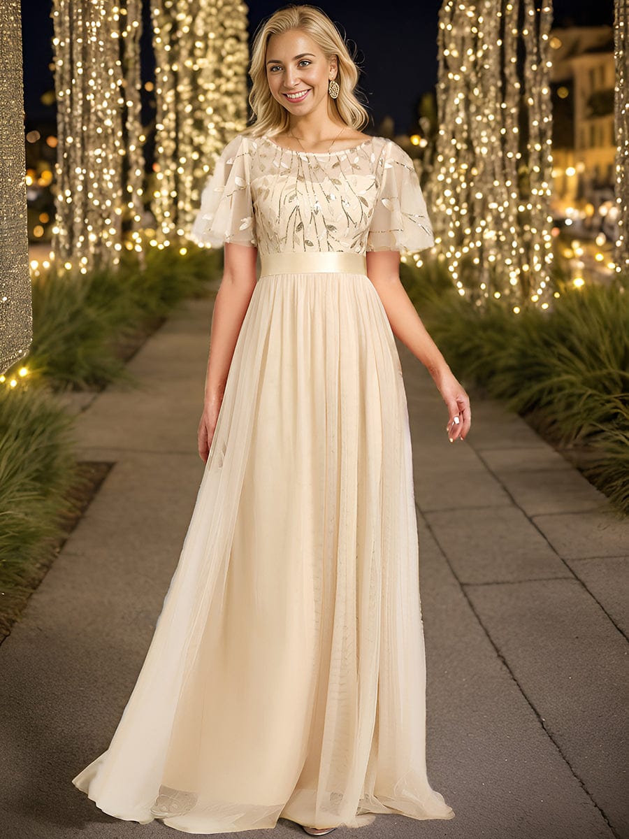 A woman in a gold Weitese A-line sequin leaf maxi dress with sleeves.