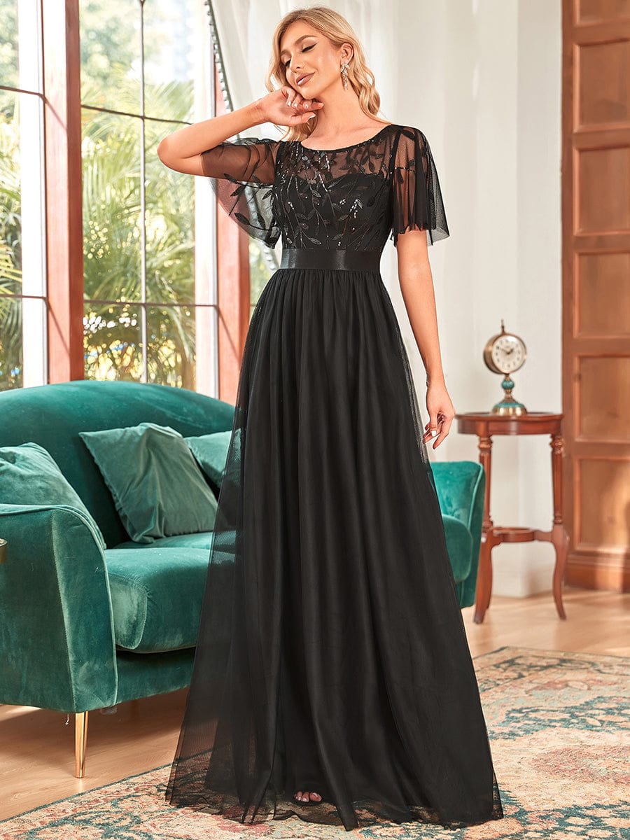 A woman in a black Weitese A-line sequin leaf maxi dress with sleeves.