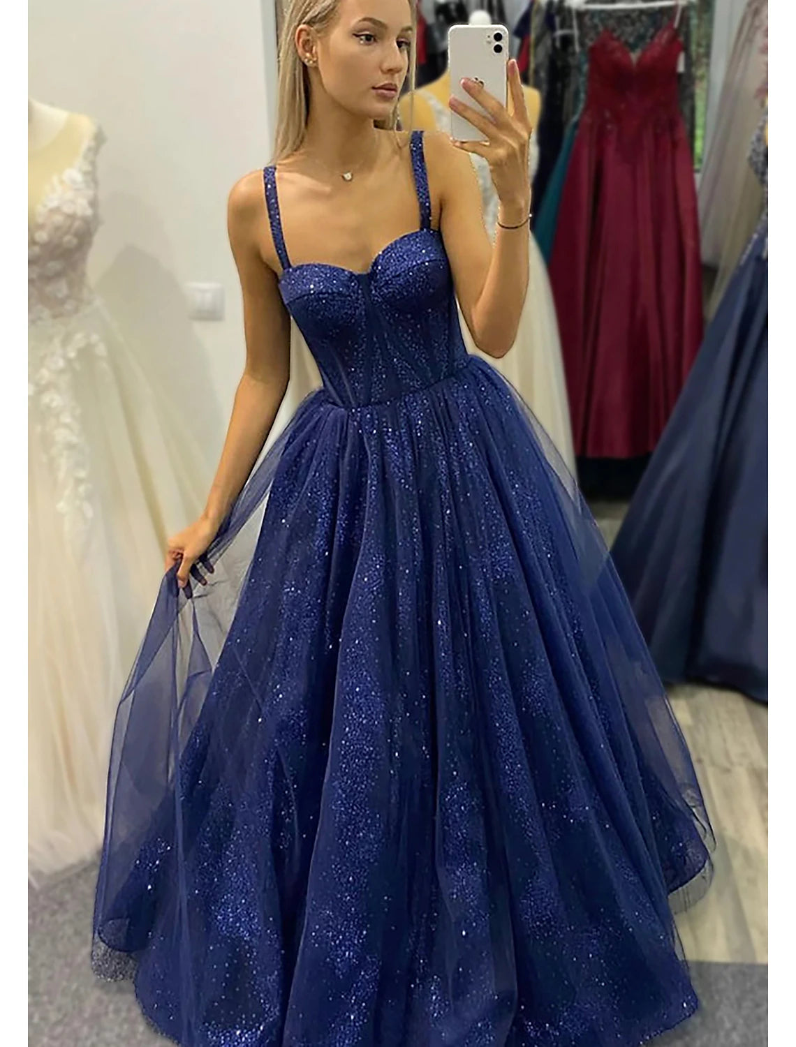 Model wearing a sparkling A-line sweetheart ball gown prom dress with glitter pleats and a backless design.