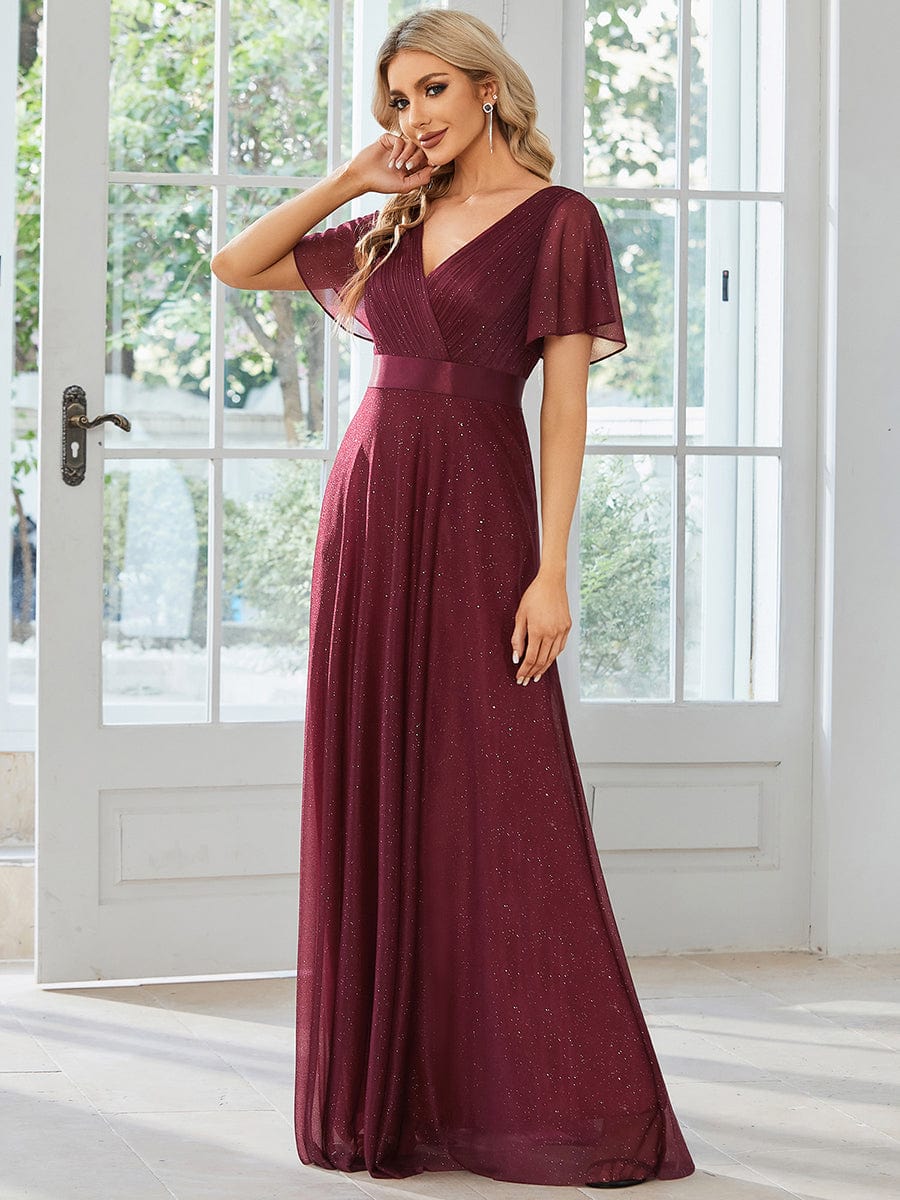Back view of model in a sparkling red A-line evening dress with a ribbon waist.