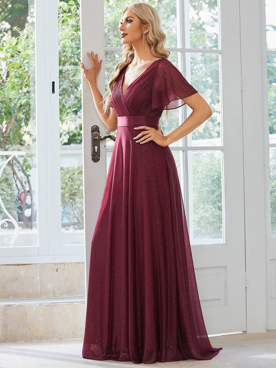 Close-up of model in a sparkling red A-line evening dress, showing V-neck and short sleeves.