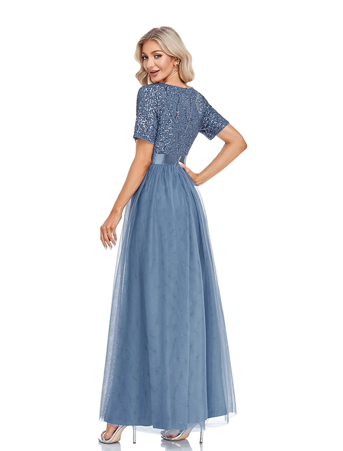 Side view of a woman in the navy sequin and tulle A-line evening gown, showing the flowing skirt.