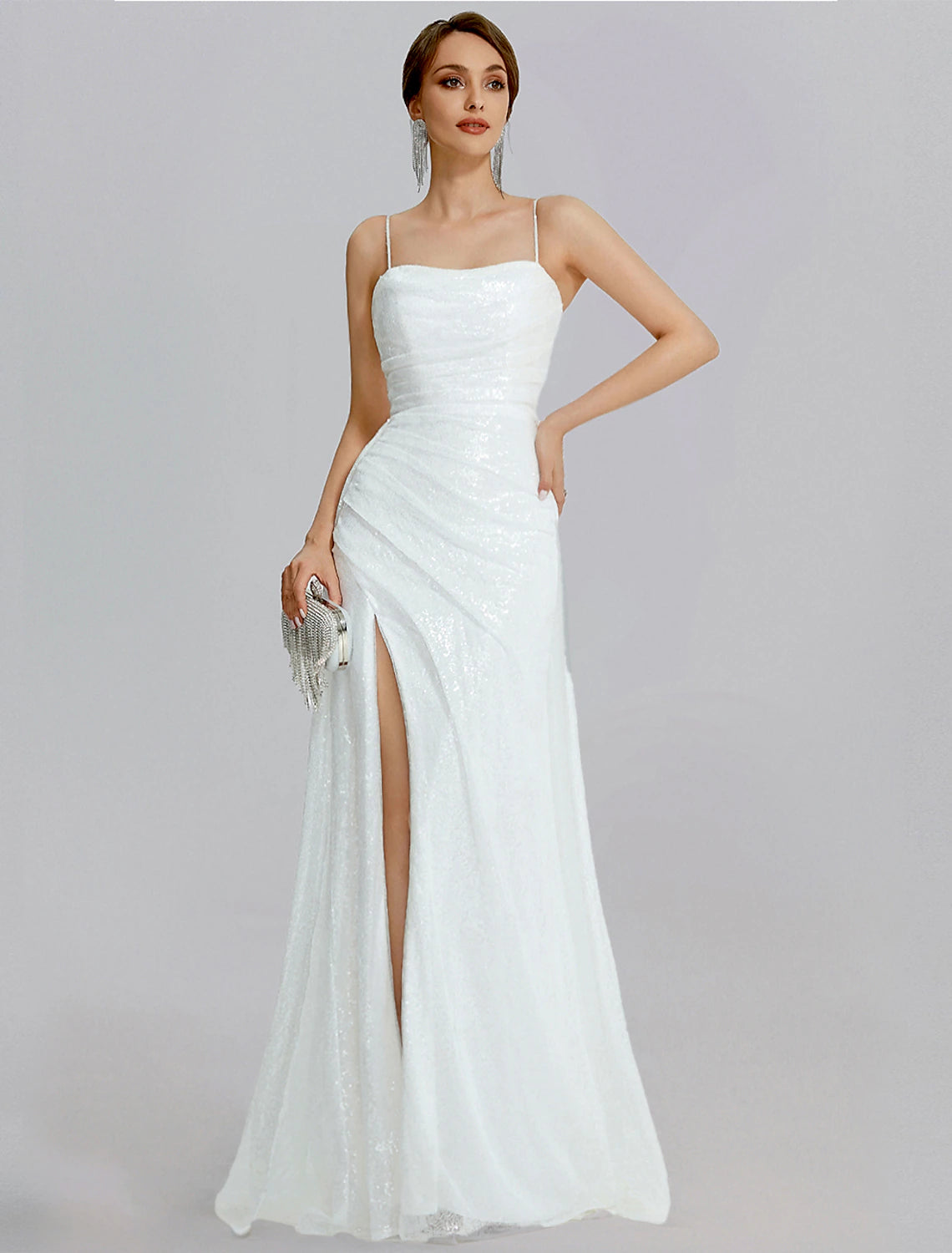 Woman posing in a sparkling sequined mermaid prom dress with cowl neck and high slit.