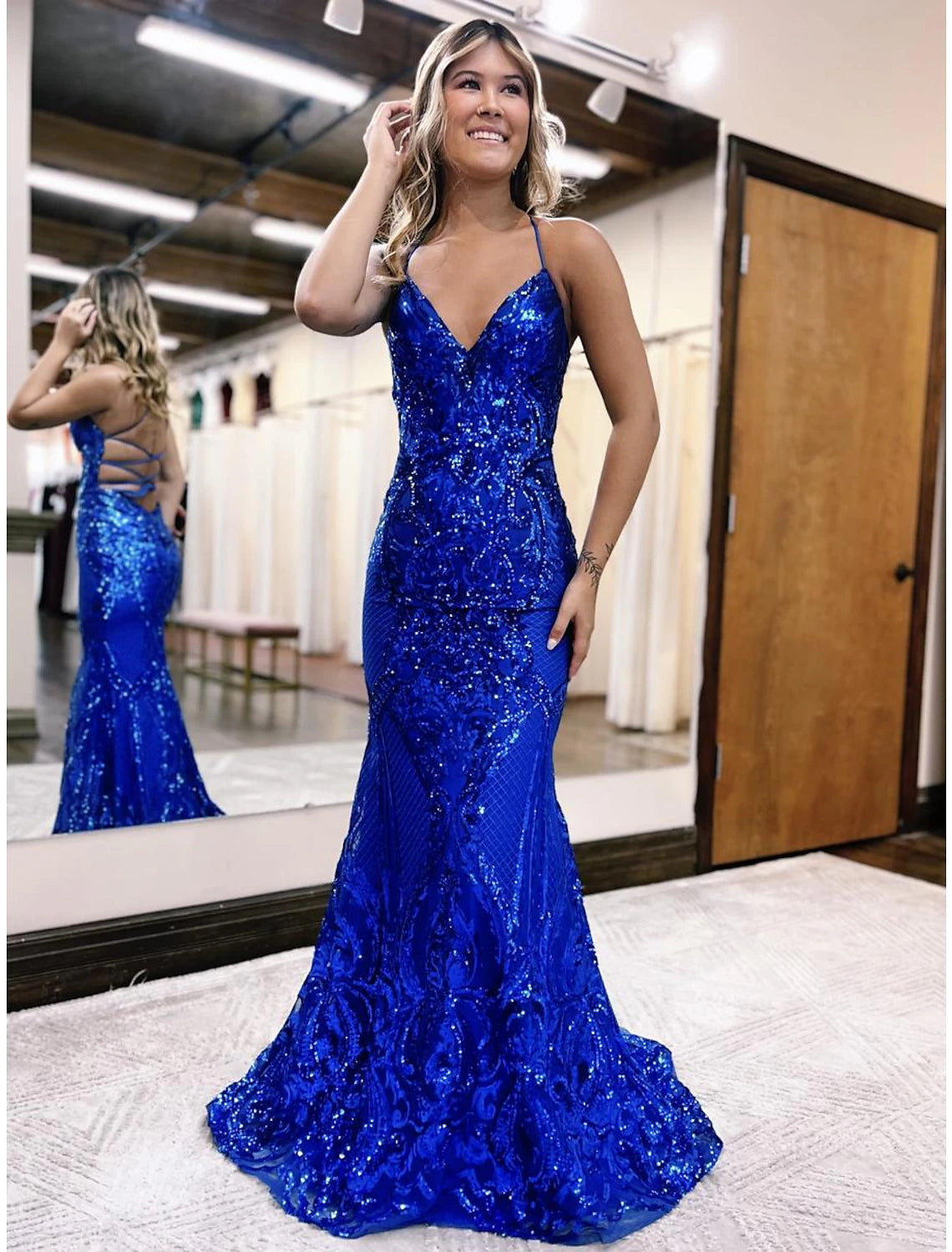 Woman wearing a sparkly V-neck mermaid trumpet prom dress with a sweep train.