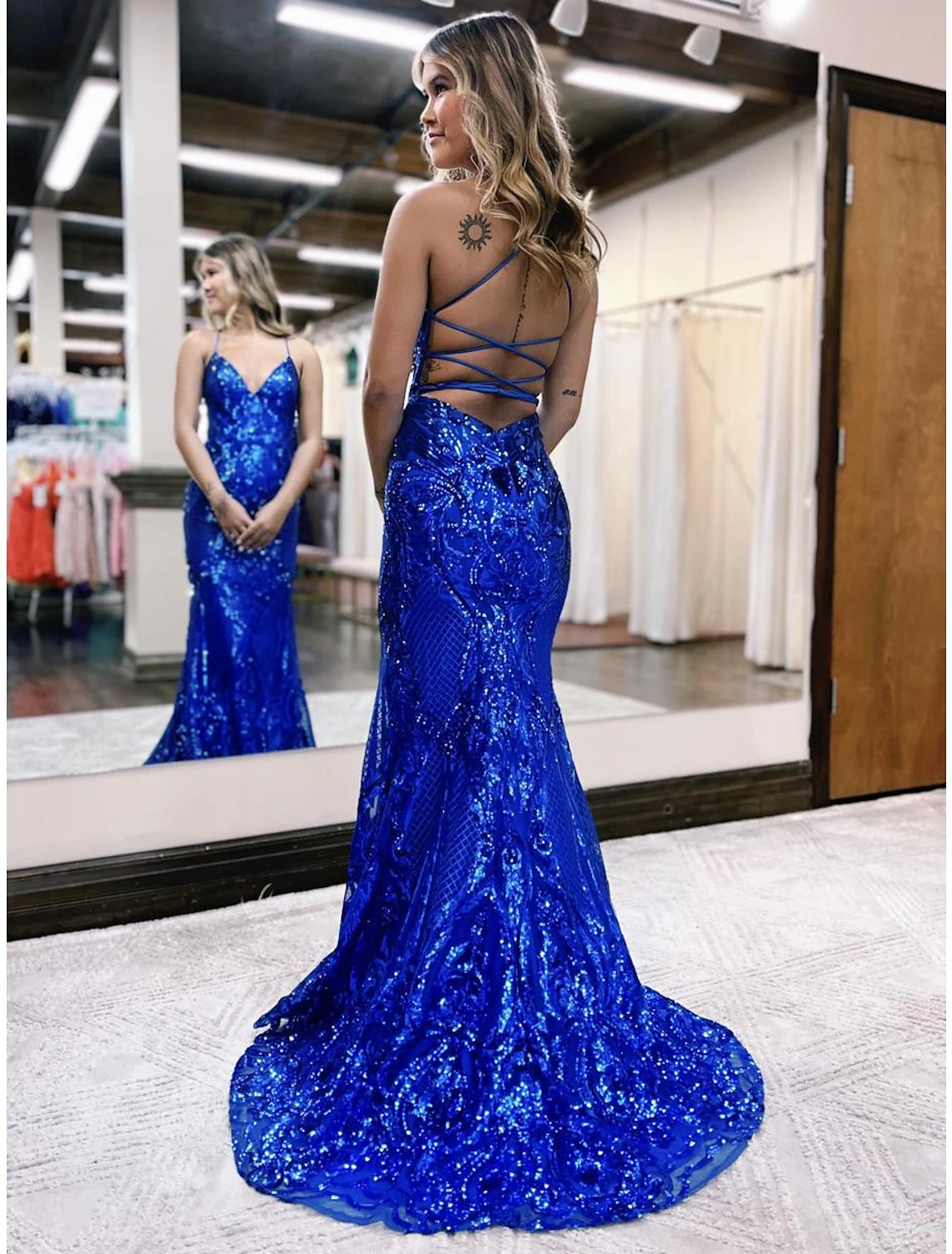Back view of a woman in a sequined backless mermaid trumpet formal gown.