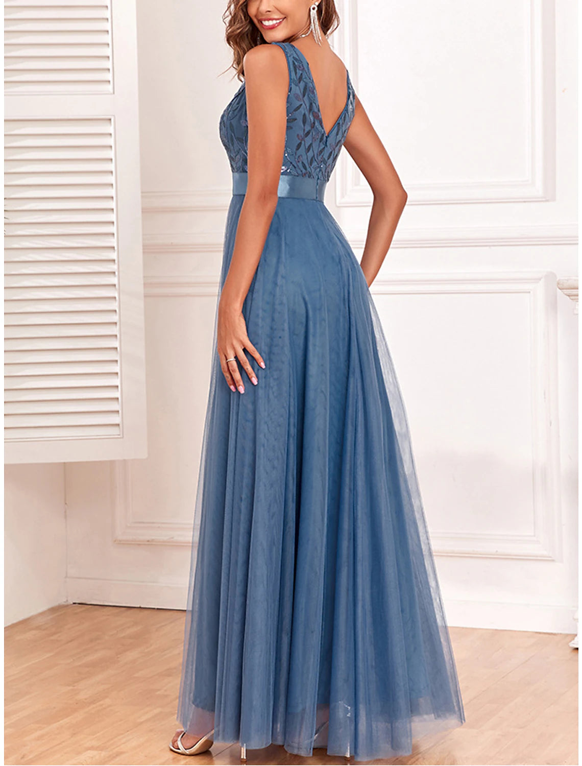 Woman wearing a sparkling blue sequin V-neck maxi dress, side view.