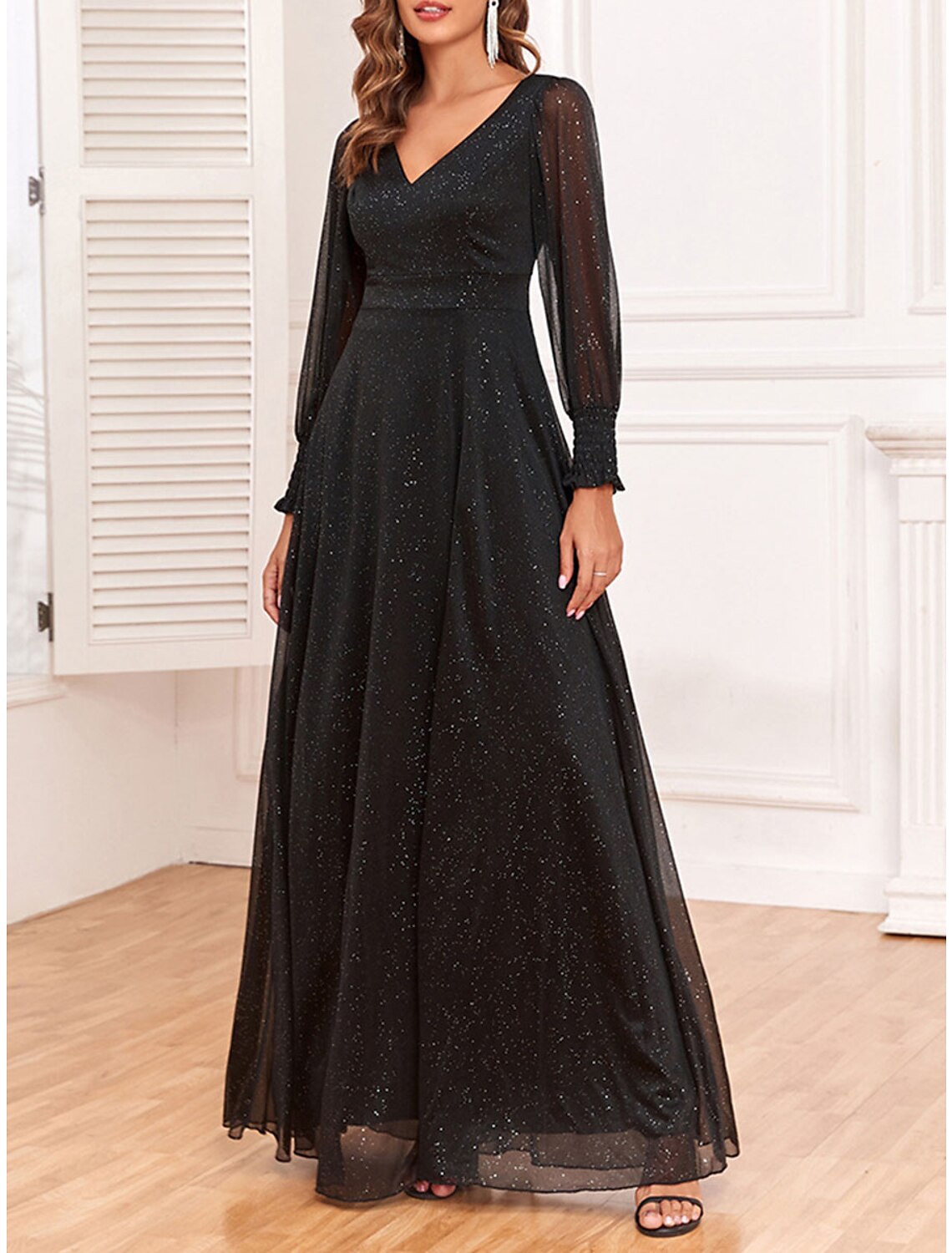 Woman posing in a black sparkly V-neck long sleeve maxi dress.