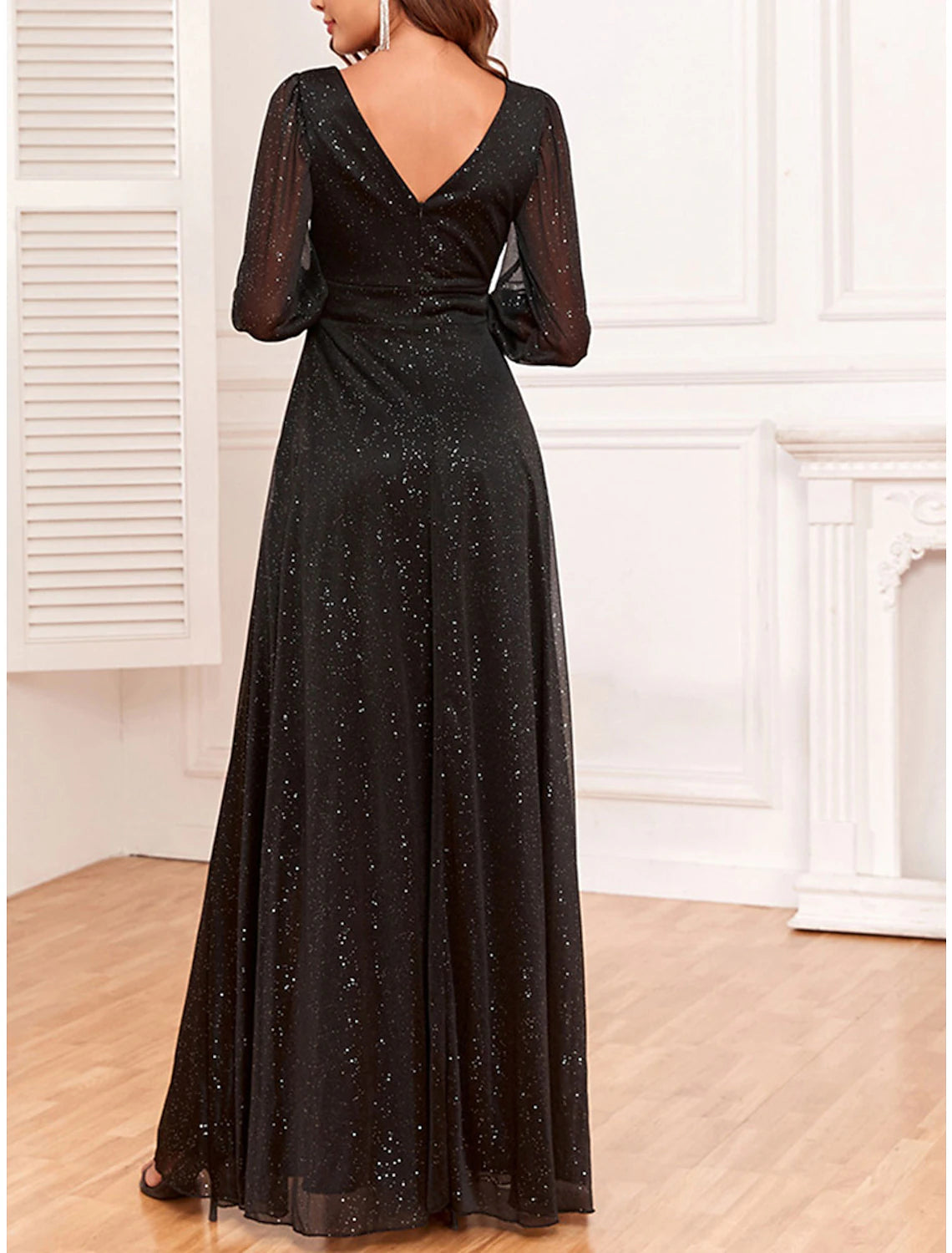 Side view of a woman in a black sparkly V-neck long sleeve maxi dress.