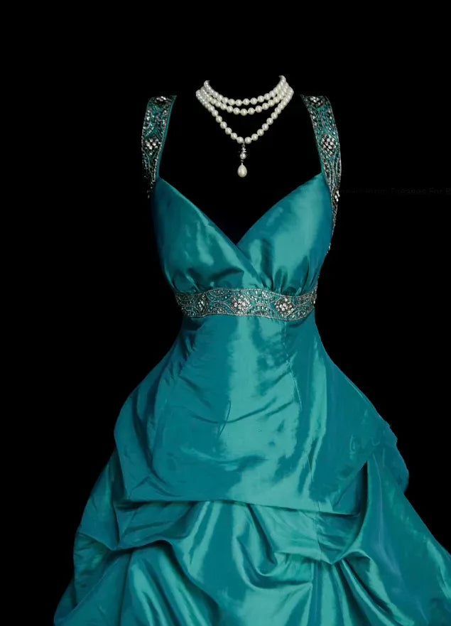 Close-up of the teal satin ball gown's bodice, detailing the beaded V-neck and lustrous fabric.
