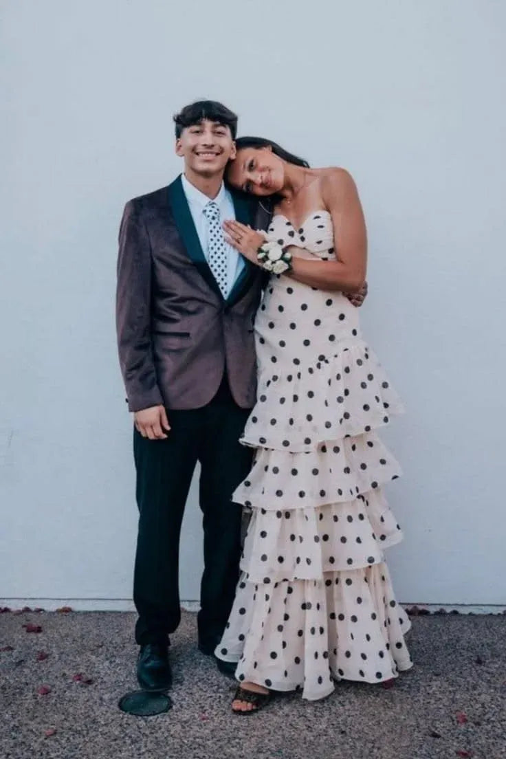 Woman wearing a full-length vintage cream polka dot strapless mermaid maxi dress with tiered ruffles.