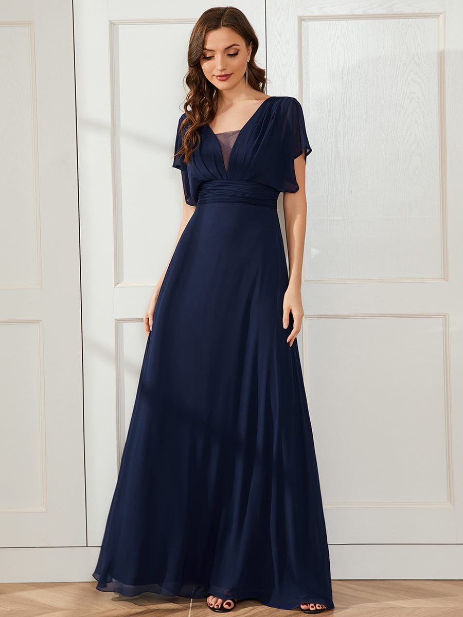 Full view of a woman in a navy blue Weitese formal chiffon gown.